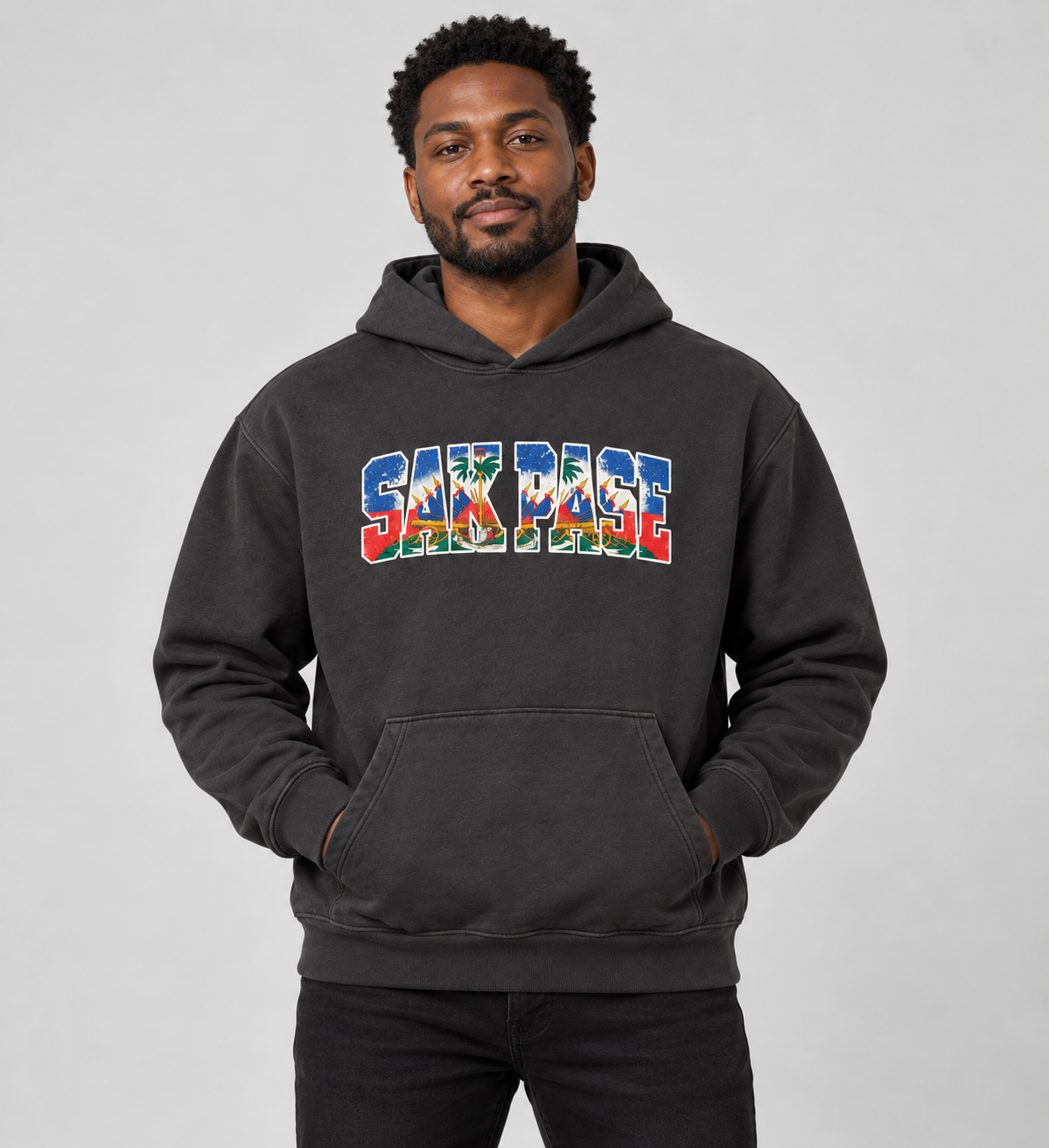 Male model wearing solid dark gray SAK PASE hoodie with smaller chest print